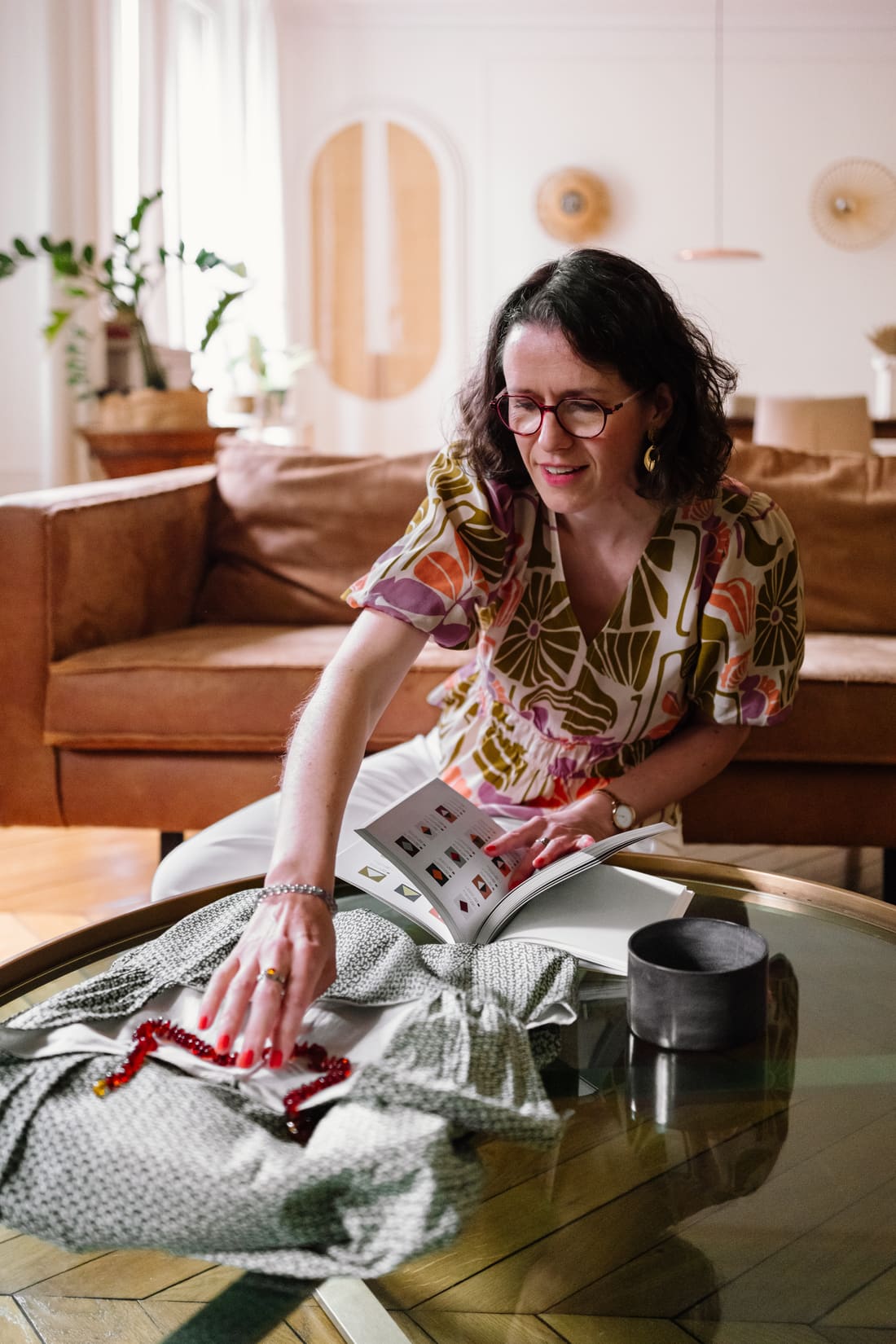 Florence feuilletant un nuancier à côté d'une robe posée sur une table basse